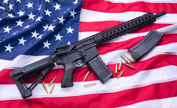 istock Custom built AR-15 carbine, bullets and a magazine on American flag surface, background. Studio shot. 956667100