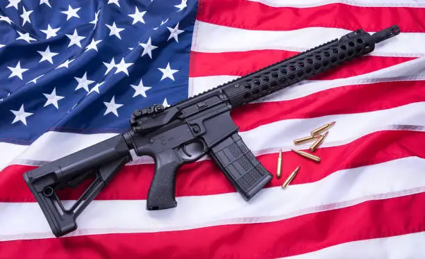 Custom built AR-15 carbine and bullets on American flag surface, background. Studio shot