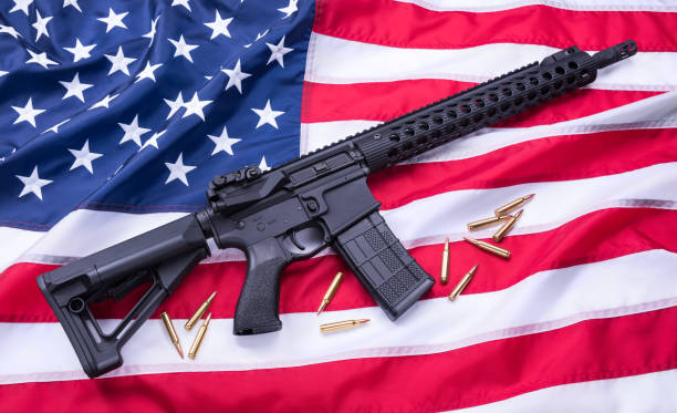 istock Custom built AR-15 carbine and bullets on American flag surface, background. Studio shot. 956667148