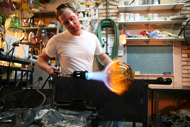 Glassblower making new glass vase in workshop stock photo