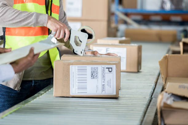 istock Unrecognizable distribution warehouse employee uses tape dispensper 956728276