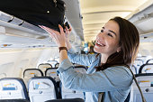 Woman places luggage in airplane's overhead compartment