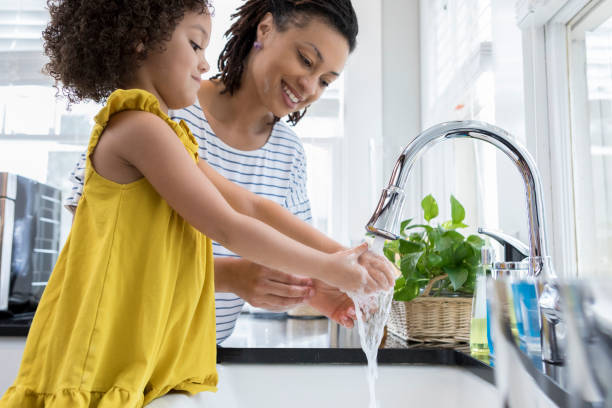 istock Cheerful mom and daughter wash hands in kitchen sink 956729630