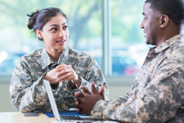 Military veterans meet to discuss recruitment Attentive new recruit talks with a senior military officer. The officer is using a laptop. camouflage clothing photos stock pictures, royalty-free photos & images