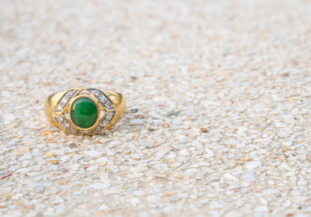 istock Closeup old green jade ring on blurred stone floor background 956732342