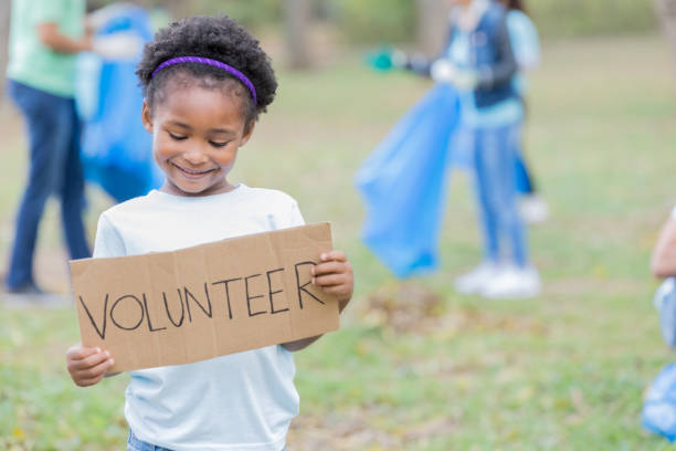 小さな女の子コミュニティ クリーンアップ プロジェクト中にボランティアの記号を保持してください。 - child little girls shy standing ストックフォトと画像
