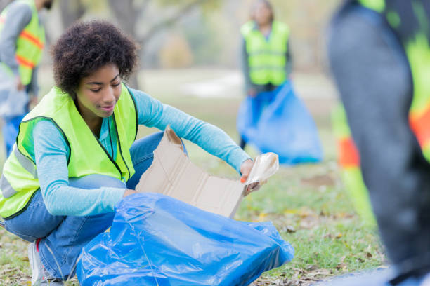 istock Young woman fills garbage bag during community cleanup project 956732840
