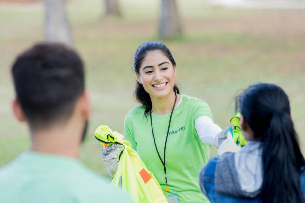 istock Young female volunteer coordinator passes out safety vests 956732852