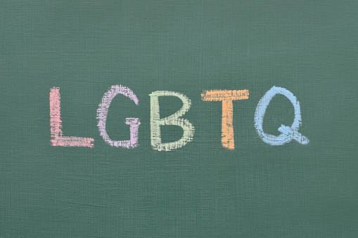 Closeup of LGBTQ spelled out on a school chalkboard in different colours symbolizing LGBTQ issues and education.