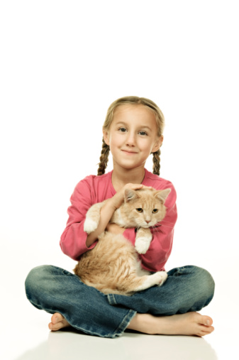 A young girl holding a cat, facing the camera.