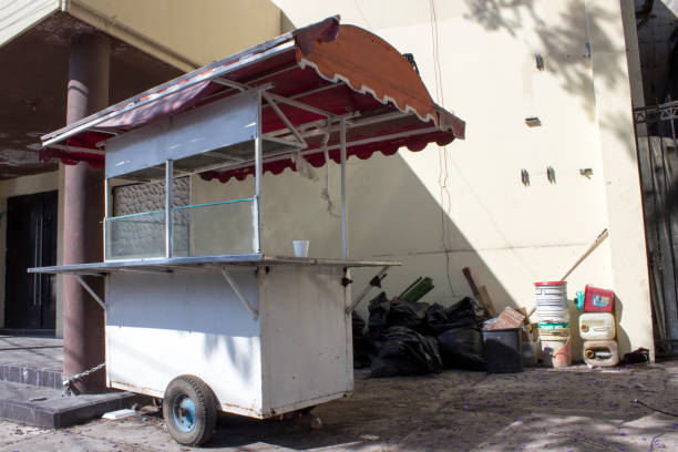 Abandoned food cart chained to an abandoned building. To the side, black trash bags and empty containers.