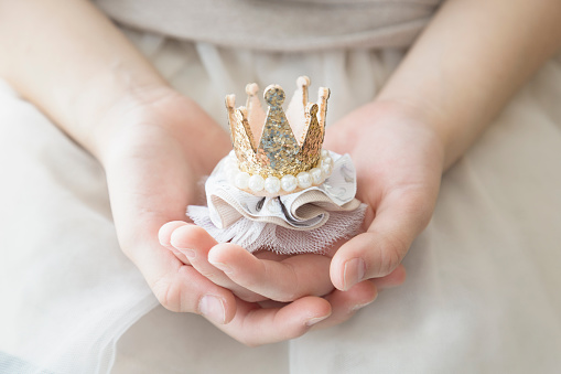 A girl holding a hand made accessory with crown shape design.