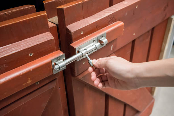 Woman hand pulling latch lock of the brown wooden fence for safety. Woman hand pulling latch lock of the brown wooden fence for safety. latch stock pictures, royalty-free photos & images