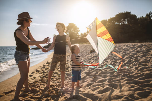 istock Mother and her sons flying a kite at the beach 956786350