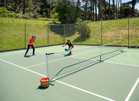 Two people Playing Pickleball outdoors ++ Public courts ++ Paddle graphics designed by photographer and applied to paddle face in PS ++