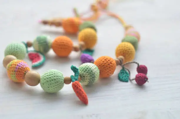 Photo of Necklace made from knitted beads and toys for the baby sitting in a sling.