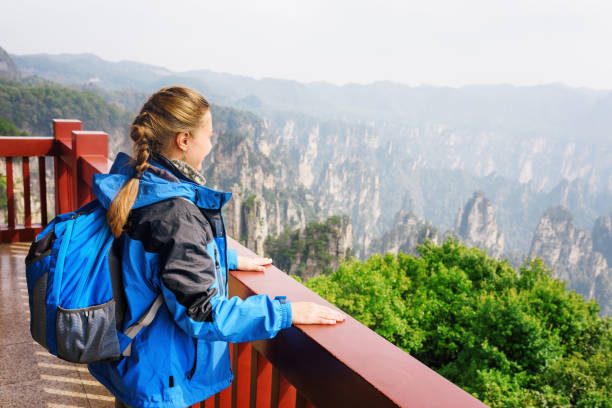 istock Young female tourist with blue backpack enjoying mountain view 956795502