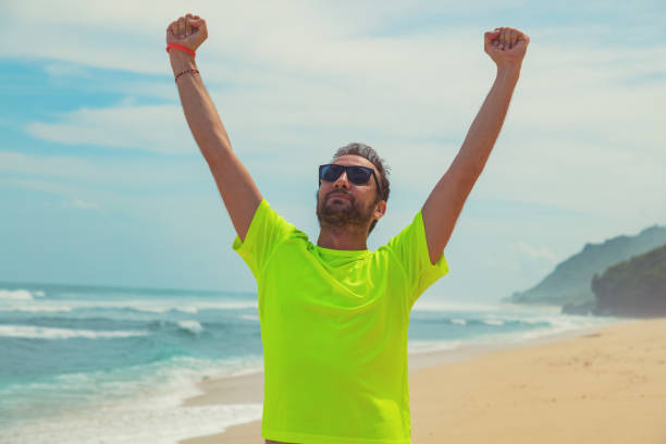 Man celebrating success after good training / exercise on a sandy ocean beach.