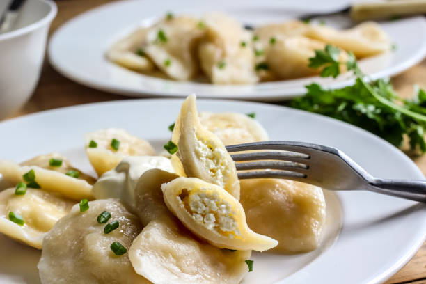 Dumplings, filled with cottage cheese Russian, Ukrainian or Polish dish: varenyky, vareniki, pierogi, pyrohy. Dumplings, filled with cottage cheese and served with sour cream. Top view pierogi stock pictures, royalty-free photos & images