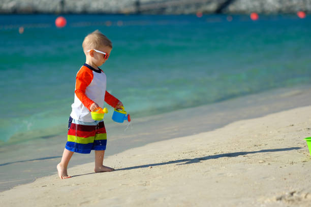 istock Two year old toddler playing on beach 956804486