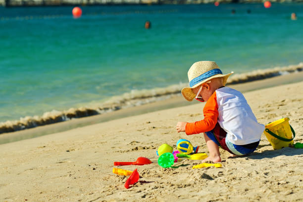 istock Two year old toddler playing on beach 956804508