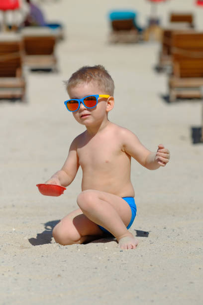 istock Toddler boy playing with shovel and sand on beach 956804526