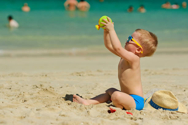 istock Two year old toddler playing on beach 956804532