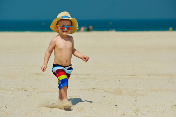 istock Two year old toddler boy running on beach 956804546