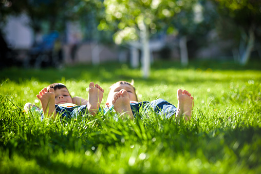 Children laying on grass. Family picnic in spring park. Image of several legs lying on the grass and resting. Relaxation happy childhood friendship concept.