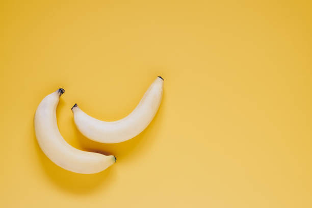 istock Two ripe sweet testy bananas on yellow background top view with copy space 956814134
