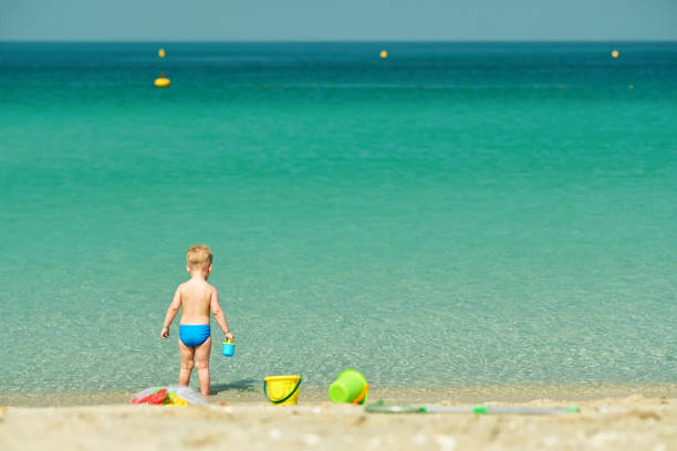 istock Two year old toddler playing on beach 956815340