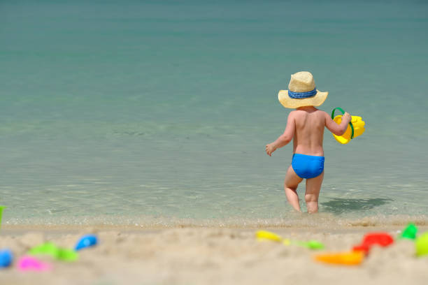 istock Two year old toddler playing on beach 956815434