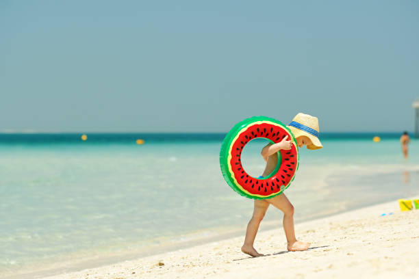 istock Toddler boy with swim ring on beach 956815462