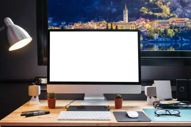 Graphic designer's workspace with a pen tablet, a computer and white backgroud for text with beautiful view of Lakecomo,Italy from Window