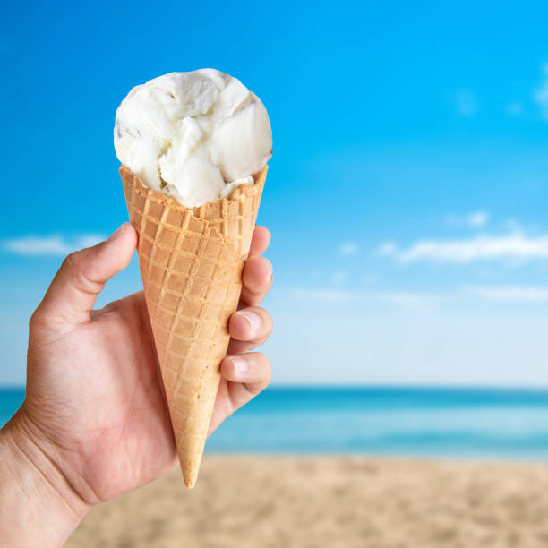 istock Hand holding ice cream cone serve in hot summer day on sky background. 956820668