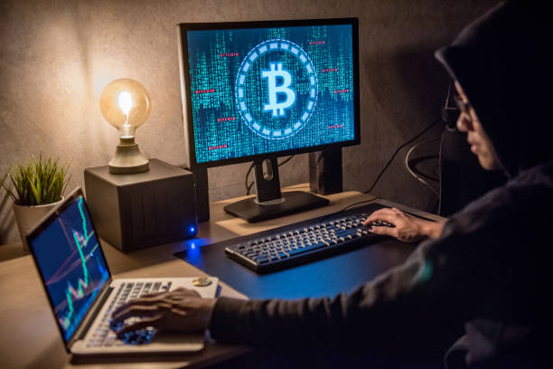 hacker man using laptop and computer with bitcoin green binary graphic and cryptocurrency candlestick graph price on monitor screen - computer hacker computer crime computer thief imagens e fotografias de stock