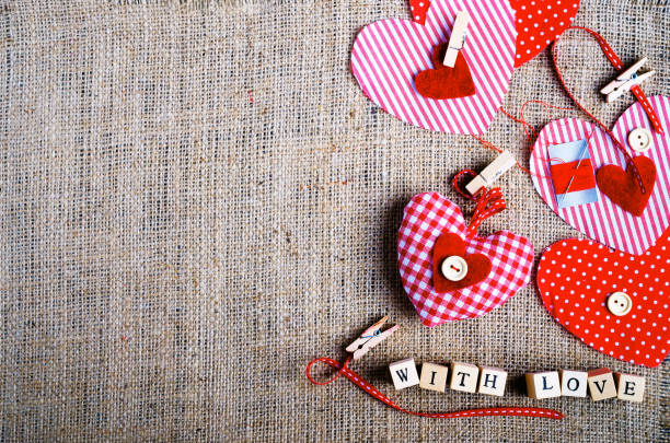 istock Sewing set: fabrics, threads, pins, buttons, tape and handmade hearts on burlap, sackcloth background. Toned 956830774