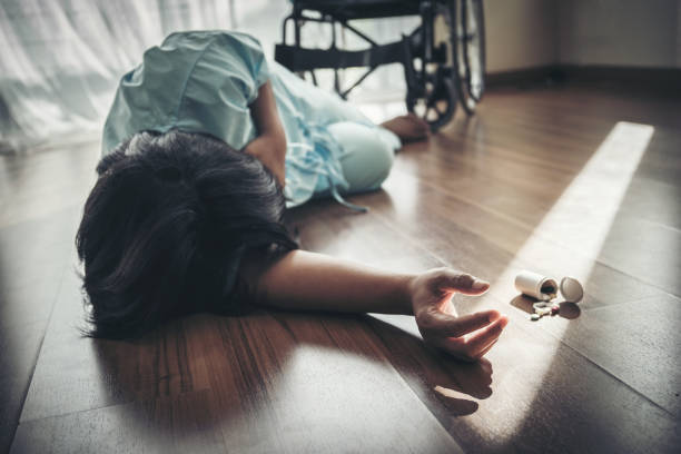 Female patients fall unconscious from a wheelchair on the floor. Heart attack, patients do not help themselves. stock photo