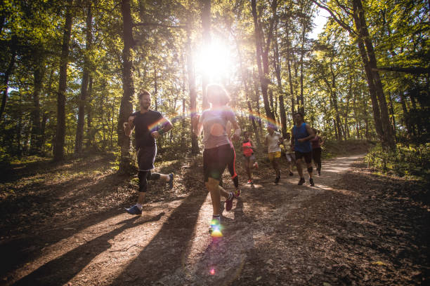 istock Group of athletic people running marathon on a path in the forest. 956837304