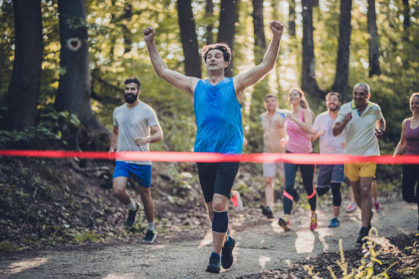 istock Successful man running through finish line and celebrating victory with his arms raised. 956839394