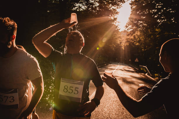 istock Male runner refreshing himself while pouring water on the face at sunset. 956839542