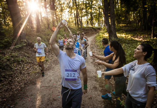 istock Man pouring water on himself while taking part in marathon race in the forest. 956839892
