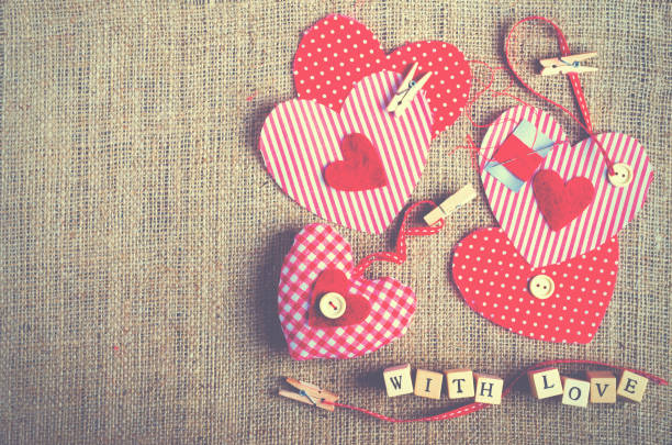 istock Red polka dot textile hearts on burlap. Free space for your text 956840122