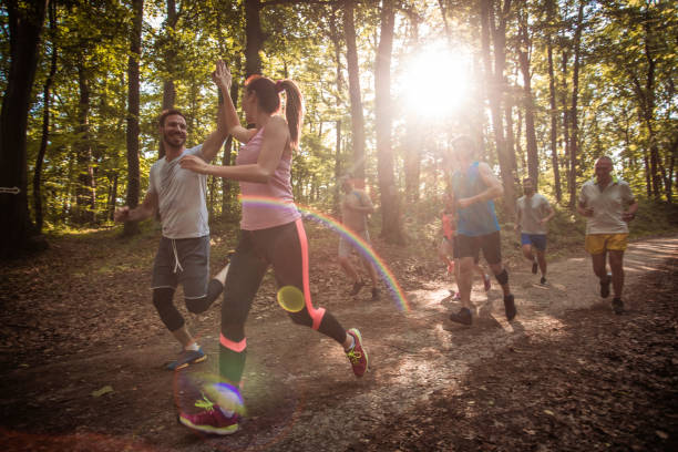 Happy couple giving high-five while running marathon race in nature.