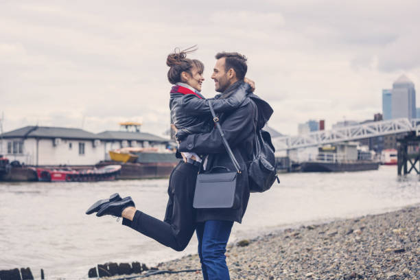 川岸、バック グラウンドで市に抱いて愛するカップル - adult autumn couple face to face ストックフォトと画像
