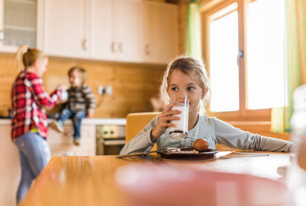 cute little girl drinking milk during breakfast in dining room. - milk child drinking little girls imagens e fotografias de stock