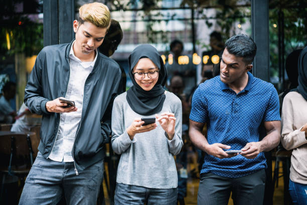 jóvenes asiáticos utilizando smartphones - adicto grupo de jóvenes amigos usando teléfonos móviles fotografías e imágenes de stock
