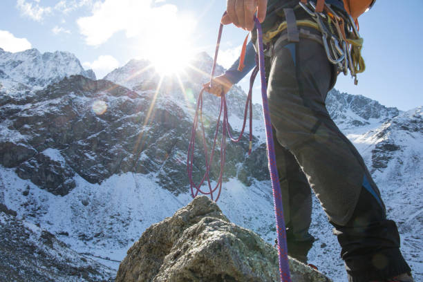 istock Low angle view of mountain climber with rope in mountains 956845252