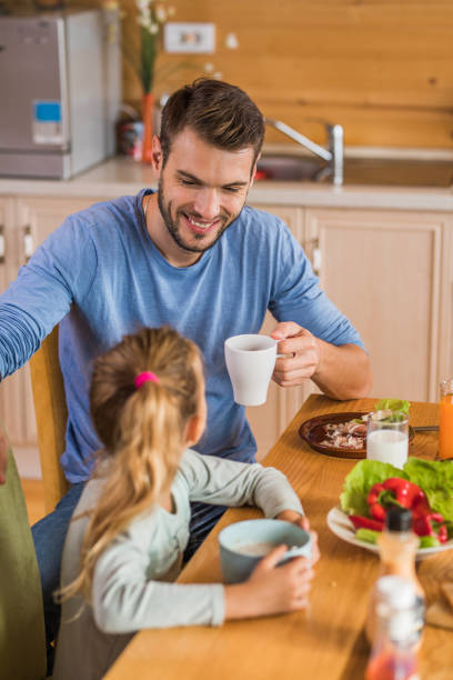 istock Happy father talking to his small daughter during breakfast at dining table. 956846112