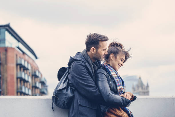 открытый выстрел счастливой пары, стоящей на мосту в лондоне - couple autumn embracing bridge стоковые фото и изображения